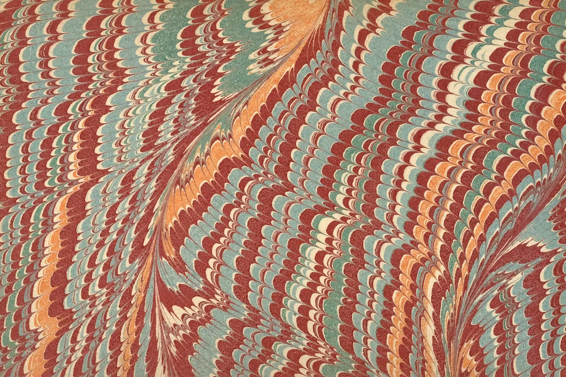 Papel marmolado con vetas onduladas en rojo, azul y naranja peinadas en paralelo